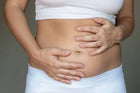 Woman holding bloated stomach, gut health and digestive wellness concept