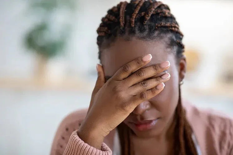 Woman holding head, appearing stressed or uncomfortable, possible headache or fatigue